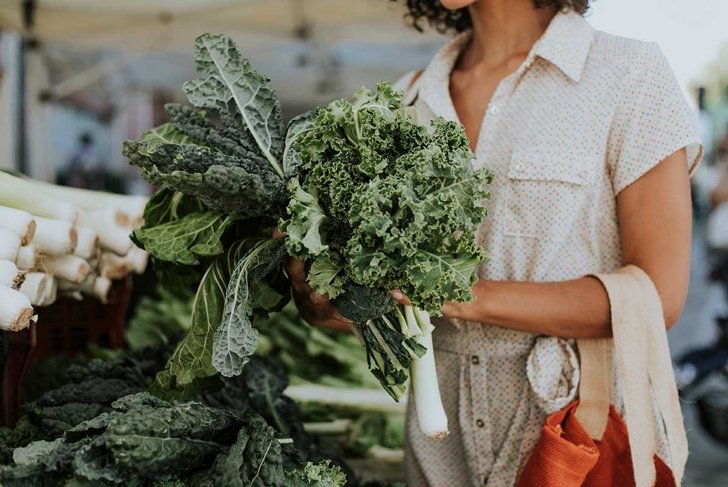 Beautiful woman buying kale at a farmers market