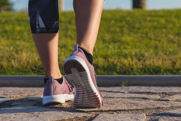 Athlete runner feet running in nature, closeup on shoe. Woman fitness jogging, active lifestyle concept