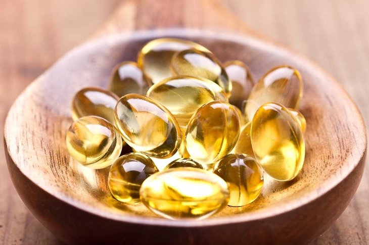 Cod liver oil omega 3 gel capsules isolated on wooden background