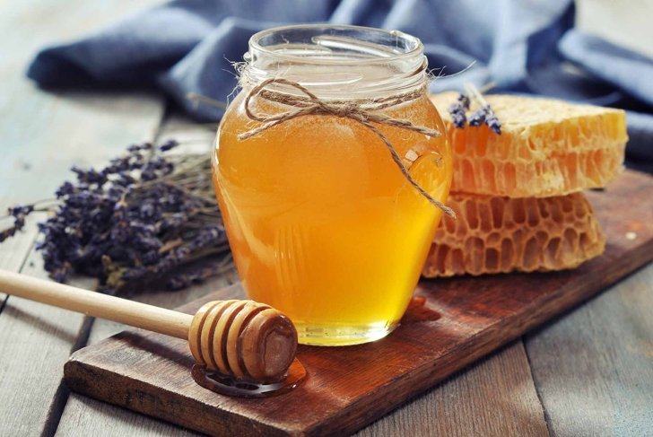 Honey in jar with honey dipper on vintage wooden background