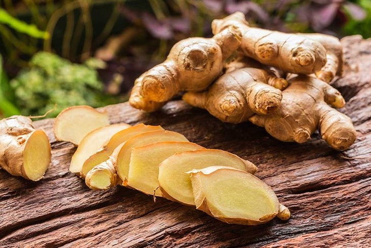 Ginger root and sliced on old plank with nature background. Close-up, Selective focus