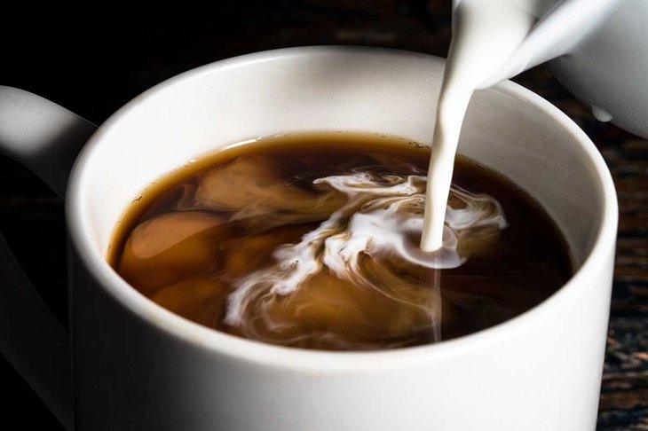 Pouring Cream into a Cup of Coffee