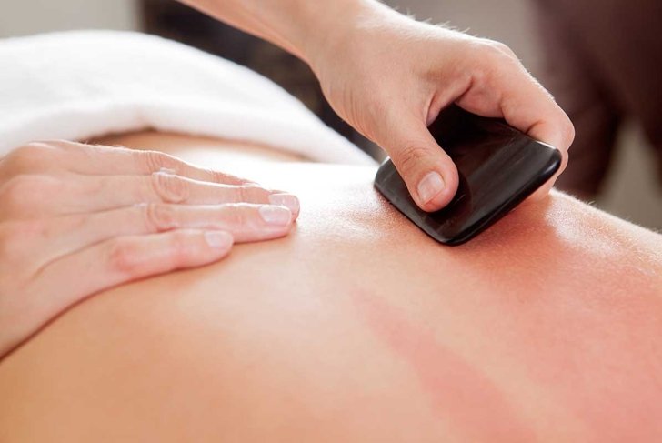 Large bone scraper tool being used ruing a guasha acupuncture treatment