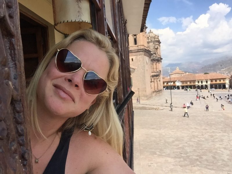 Paulette Perhach takes a selfie as she leans slightly out an open window on an upper floor of a building