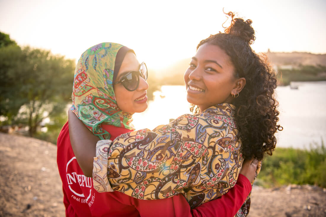 Two women arm-in-arm representing Intrepid Travel